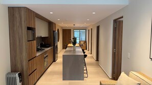 A modern kitchen with a central island, wooden cabinetry, and a dining area with a view. - w Welcoming 2BR w Private Terrace in Hipodromo (Mexico City)