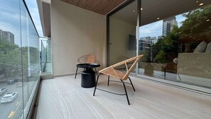 A balcony with a glass door, wicker chairs, a small round table, and a view of the cityscape. - w Welcoming 2BR w Private Terrace in Hipodromo (Mexico City)