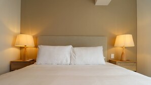 A neatly made bed with white linens, two bedside lamps, and a wooden nightstand. - w Luxury Cozy 2BR w Balcony in Miraflores (Lima)