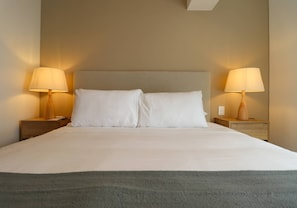 A neatly made bed with white linens, two bedside lamps, and a wooden nightstand. - w Luxury Cozy 2BR w Balcony in Miraflores (Lima)