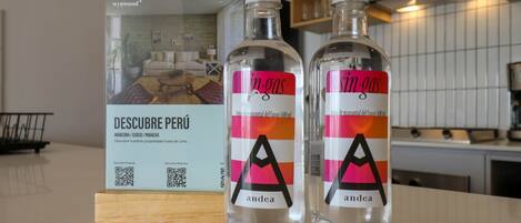 Two bottles of Andea water with a QR code and a brochure for a property named 'DESCUBRE PERÚ'.