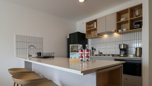 A modern kitchen with a central island, bar stools, a coffee machine, and a built-in oven. - w Luxury Cozy 2BR w Balcony in Miraflores (Lima)