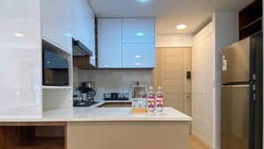 Eine moderne Küche mit weißen Schränken, einem Edelstahlkühlschrank und einer Kaffeemaschine.