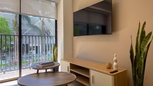 Ein modernes Zimmer mit einer großen Schiebeglastür, einem wandmontierten Flachbildfernseher, einem Holzschminktisch und einer Topfpflanze.