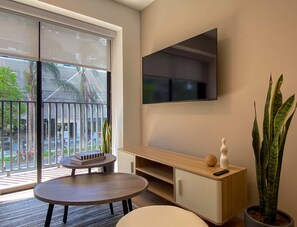 Ein modernes Zimmer mit einer großen Schiebeglastür, einem wandmontierten Flachbildfernseher, einem Holzschminktisch und einer Topfpflanze.
