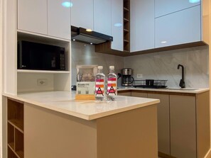 Eine moderne Küche mit weißen Schränken, einer Mikrowelle, einer Kaffeemaschine und zwei Wasserflaschen auf der Arbeitsfläche.
