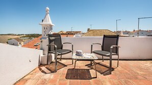 A rooftop terrace with two chairs, a small table, and a decorative tower. - Casa M.V. Slater - CharmingTavira Townhouse with Rooftop Terrace (Pet friendly) (Tavira)