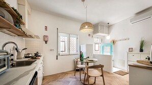 A kitchen with a sink, stove, and dining area with chairs and a table. - Casa M.V. Slater - CharmingTavira Townhouse with Rooftop Terrace (Pet friendly) (Tavira)
