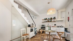 A modern kitchen with a staircase, white cabinetry, and a hanging light fixture. - Casa M.V. Slater - CharmingTavira Townhouse with Rooftop Terrace (Pet friendly) (Tavira)