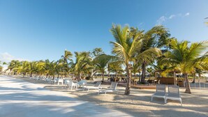 A beach with white lounge chairs and palm trees. - NOK Luxury 1BR Apartment The Towers by Vistacana (Punta Cana)
