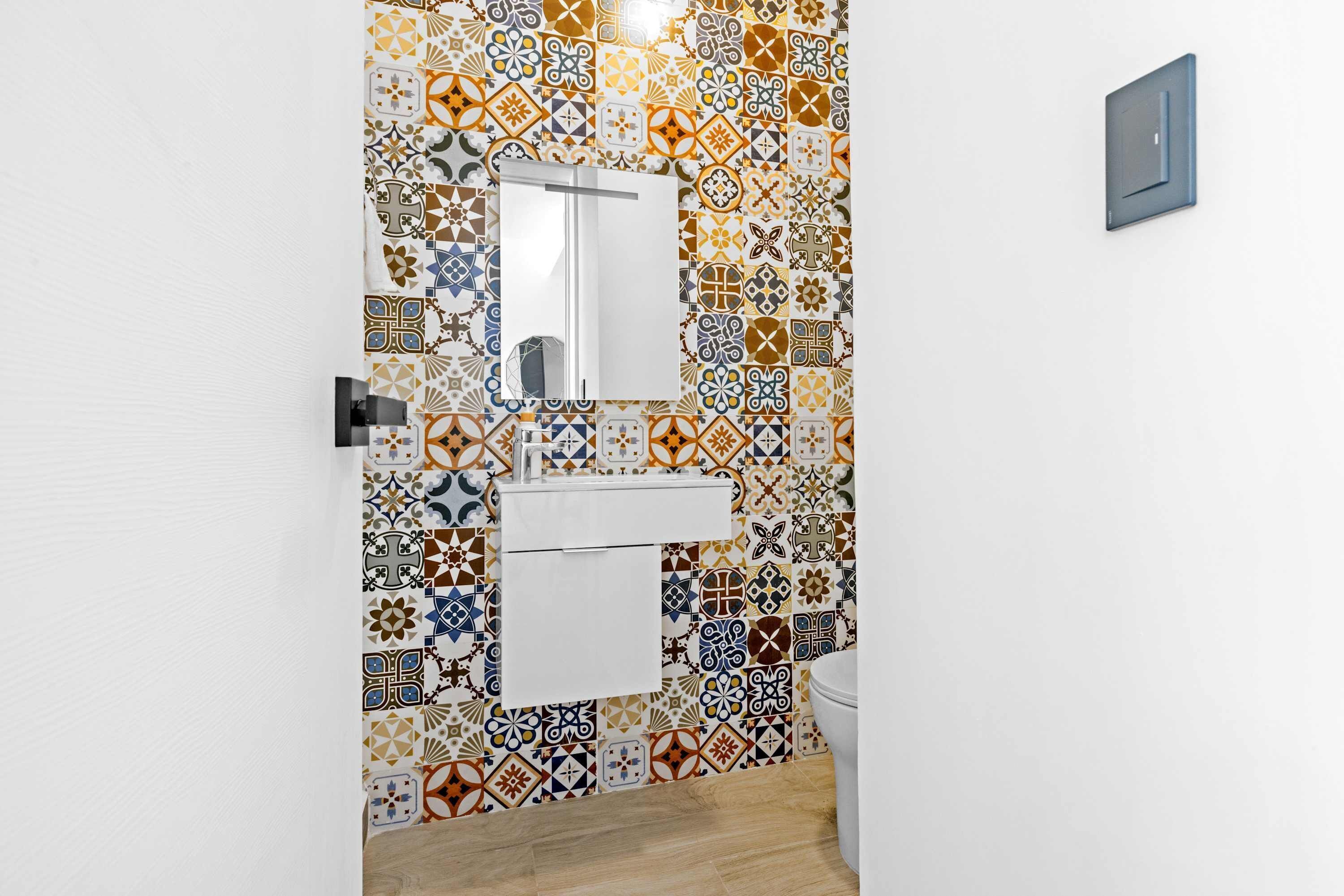 Une salle de bain avec un mur carrelé, un miroir, un lavabo et des toilettes.