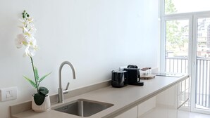 Una cucina moderna con un lavello, una macchina da caffè e un'orchidea in vaso.