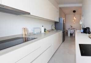 A modern kitchen with white cabinetry, a black countertop, a built-in stove, and a dining area with a table and chairs. - One Lux Stay 2br/2ba Antwerp Near Central Station (Antwerp)