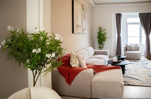 A living room with a sofa, a coffee table, a potted plant, and a window with curtains. - One Lux Stay 2br/2ba Antwerp Near Central Station (Antwerp)