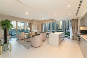 A modern living room with a sofa, coffee table, and a dining area. - One Lux Stay Grande Signature Residence 2BR - Direct Burj Khalifa View (Dubai)