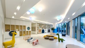 Ein moderner Kinderspielbereich mit bunten Tiermodellen, einem großen Fenster und einer weißen Decke mit integrierter Beleuchtung.