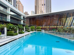 A modern hotel with a swimming pool, glass railings, and a view of the city skyline. - One Lux Stay Grande Signature Residence 2BR - Direct Burj Khalifa View (Dubai)