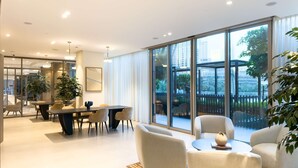 Ein modernes Interieur mit Essbereich, Sofas und großen Fenstern mit Blick auf die Stadt.