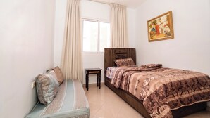 Une chambre à coucher comprenant un lit, une table de chevet, un banc, une fenêtre avec des rideaux et un tableau accroché au mur.