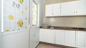 Une cuisine avec des meubles blancs, un plan de travail en granit et une fenêtre donnant sur un paysage verdoyant.