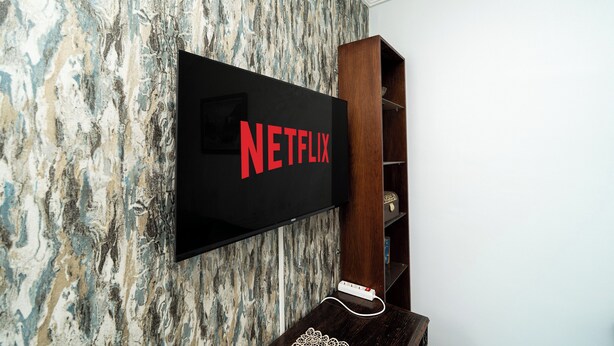 Un téléviseur à écran plat fixé à un mur texturé, avec un meuble en bois placé en dessous.