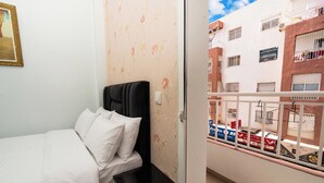 Une chambre avec un lit, une table de chevet et une vue sur le balcon extérieur.
