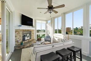 A sunlit room with a fireplace, a television, a sofa, and a ceiling fan. - Stunning Harbor Island Home, Ocean Views, Golf Cart, Walk to Beach & Resort Amenities Included! (Saint Helena)