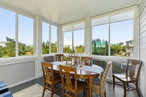 A sunroom with a large table and chairs, large windows, and a view of greenery outside. - Stunning Harbor Island Home, Ocean Views, Golf Cart, Walk to Beach & Resort Amenities Included! (Saint Helena)