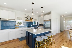 A modern kitchen with a large island, bar stools, and pendant lighting. - Stunning Harbor Island Home, Ocean Views, Golf Cart, Walk to Beach & Resort Amenities Included! (Saint Helena)