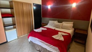 A bedroom with a bed, a wardrobe, and a red wall. - Pousada Village Da Serra (Santana do Riacho)