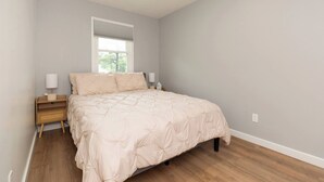 Een slaapkamer met een bed, nachtkastjes, een spiegel en een raam.