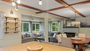 A spacious living area with a wooden dining table, a sofa set, and a fireplace. - Lovely home walking distance to community beach sleeps 6 (Moultonborough)