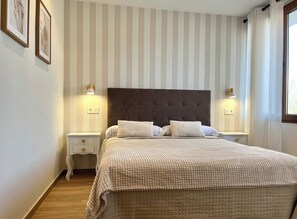 A bedroom with a large bed, two bedside tables, and a striped wall. - Apartment in the Picos de Europa, Asturias. (Onis)