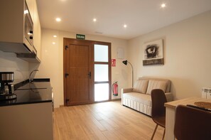 A modern kitchen with a coffee machine, a wooden door, a sofa, and a painting on the wall. - Apartment in the Picos de Europa, Asturias. (Onis)