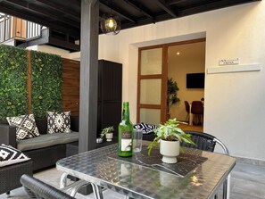 A modern outdoor seating area with a glass table, a bottle of Arbusul, and a potted plant. - Apartment in the Picos de Europa, Asturias. (Onis)