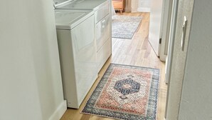 A laundry area with a washing machine, dryer, and cabinets. A patterned rug is on the floor. - Perfect 3-bedroom townhome walking distance to Whole Foods in Santa Rosa (Santa Rosa)