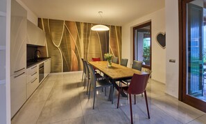 A modern dining area with a wooden table, chairs, and a decorative wall. - Villa Vittoria  (Oliveto Lario)
