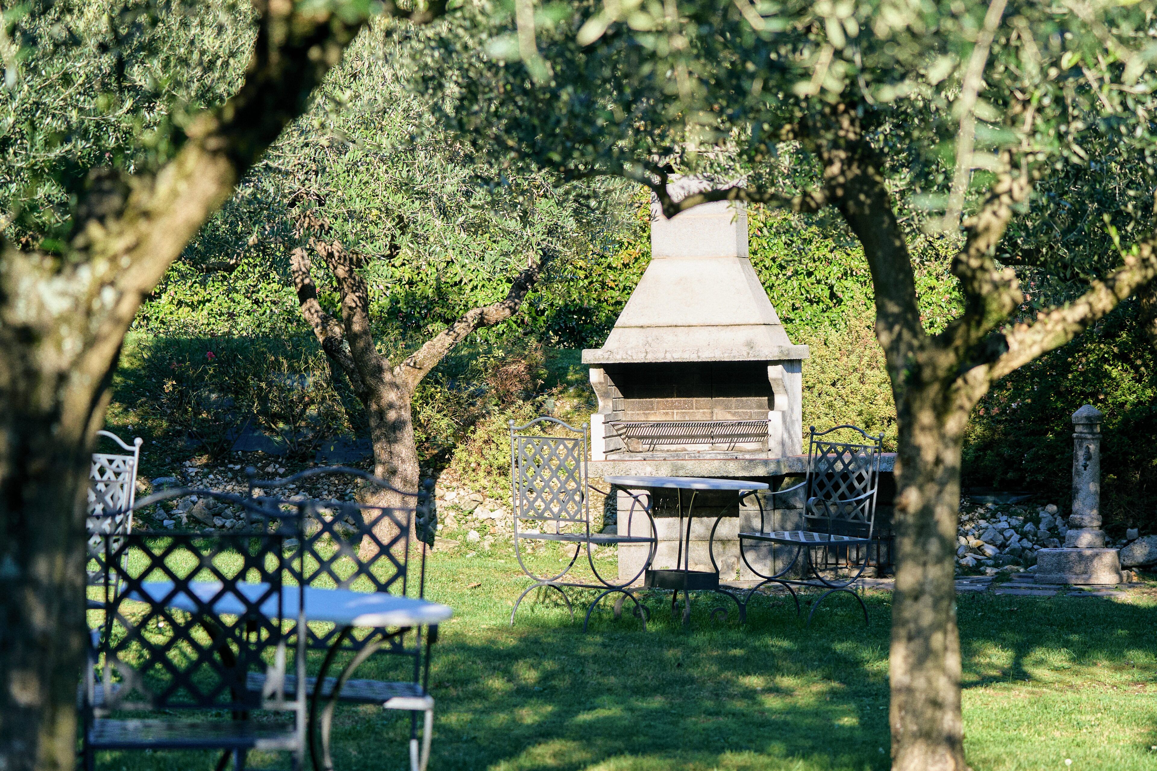 A barbecue grill in a garden with a table and chairs.