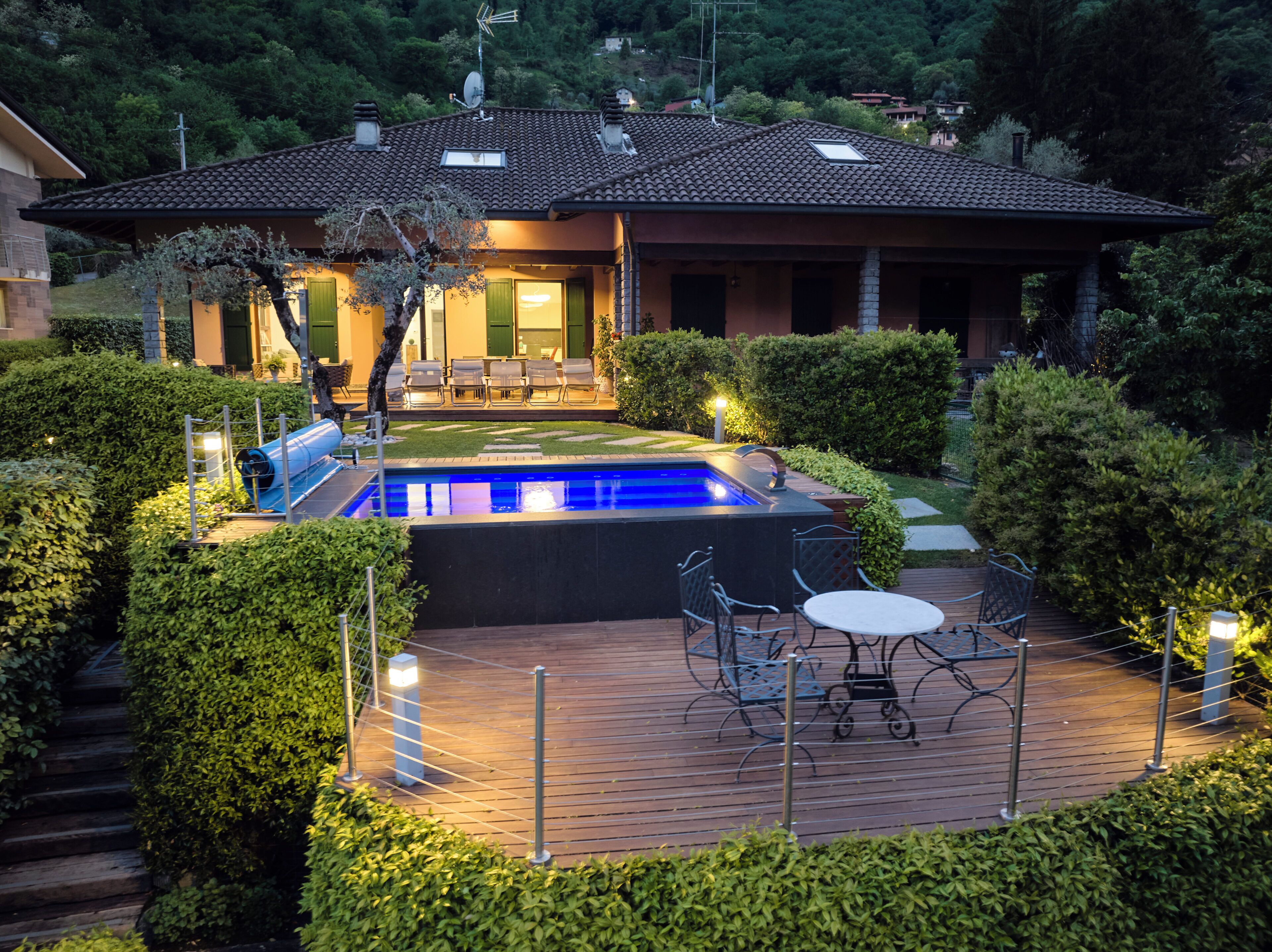 Una casa con piscina, zona de estar exterior y jardín cuidado.