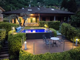 Una casa con piscina, zona de estar exterior y jardín cuidado.