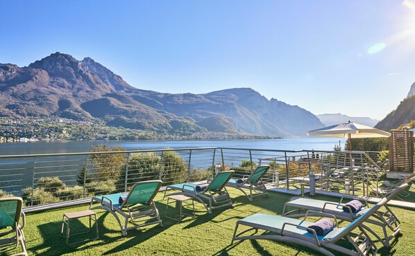 A terrace with lounge chairs overlooking a lake and mountains. - Villa Vittoria (Oliveto Lario)