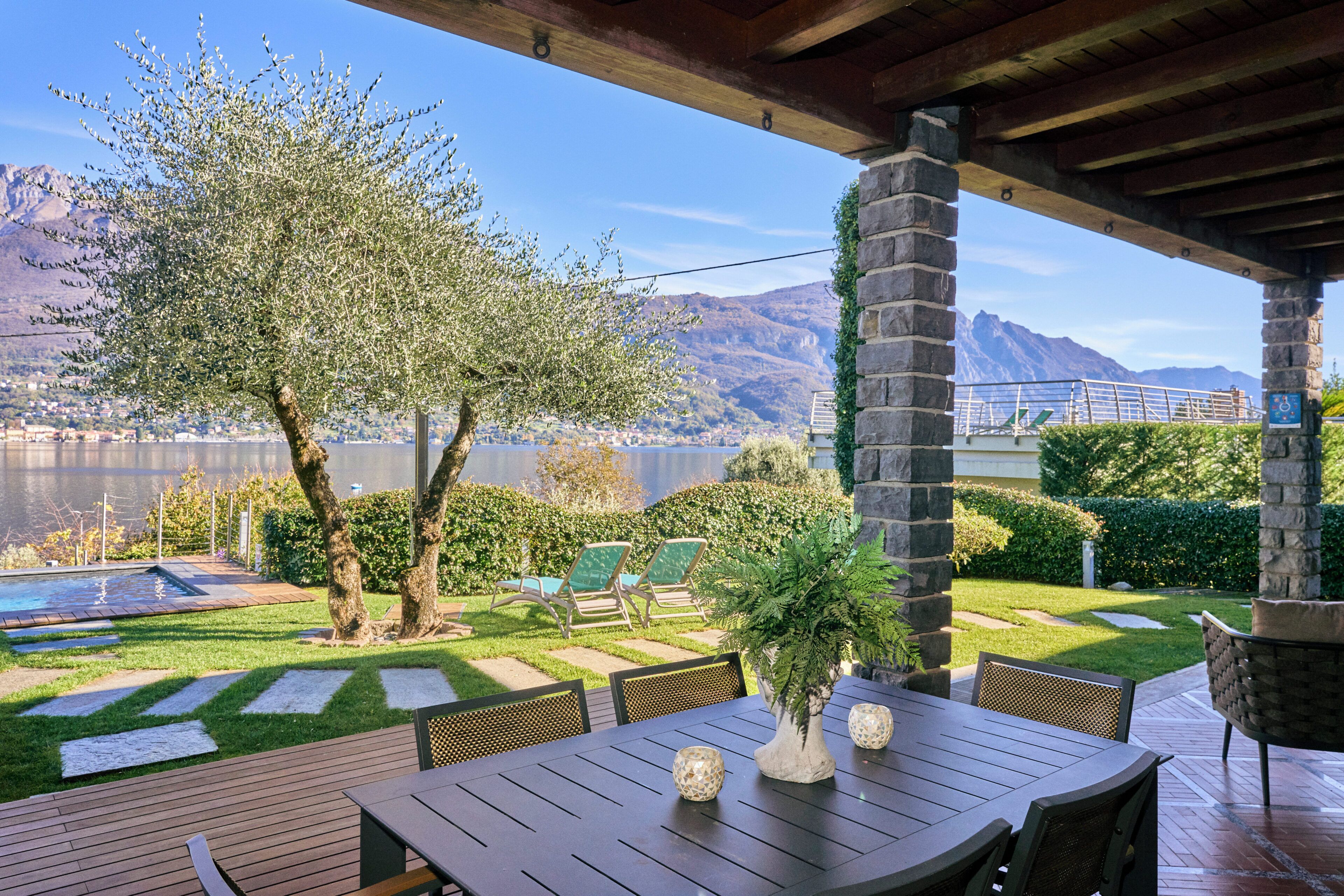 An outdoor patio with a table, chairs, and a view of a lake and mountains.
