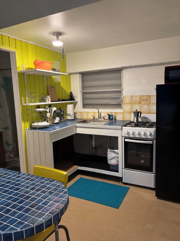Una cocina compacta con lavamanos, estufa y ventana sobre el lavamanos.