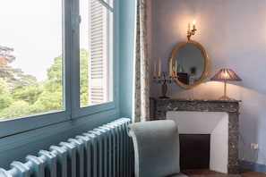 Una habitació amb xemeneia, mirall, làmpada i radiador.