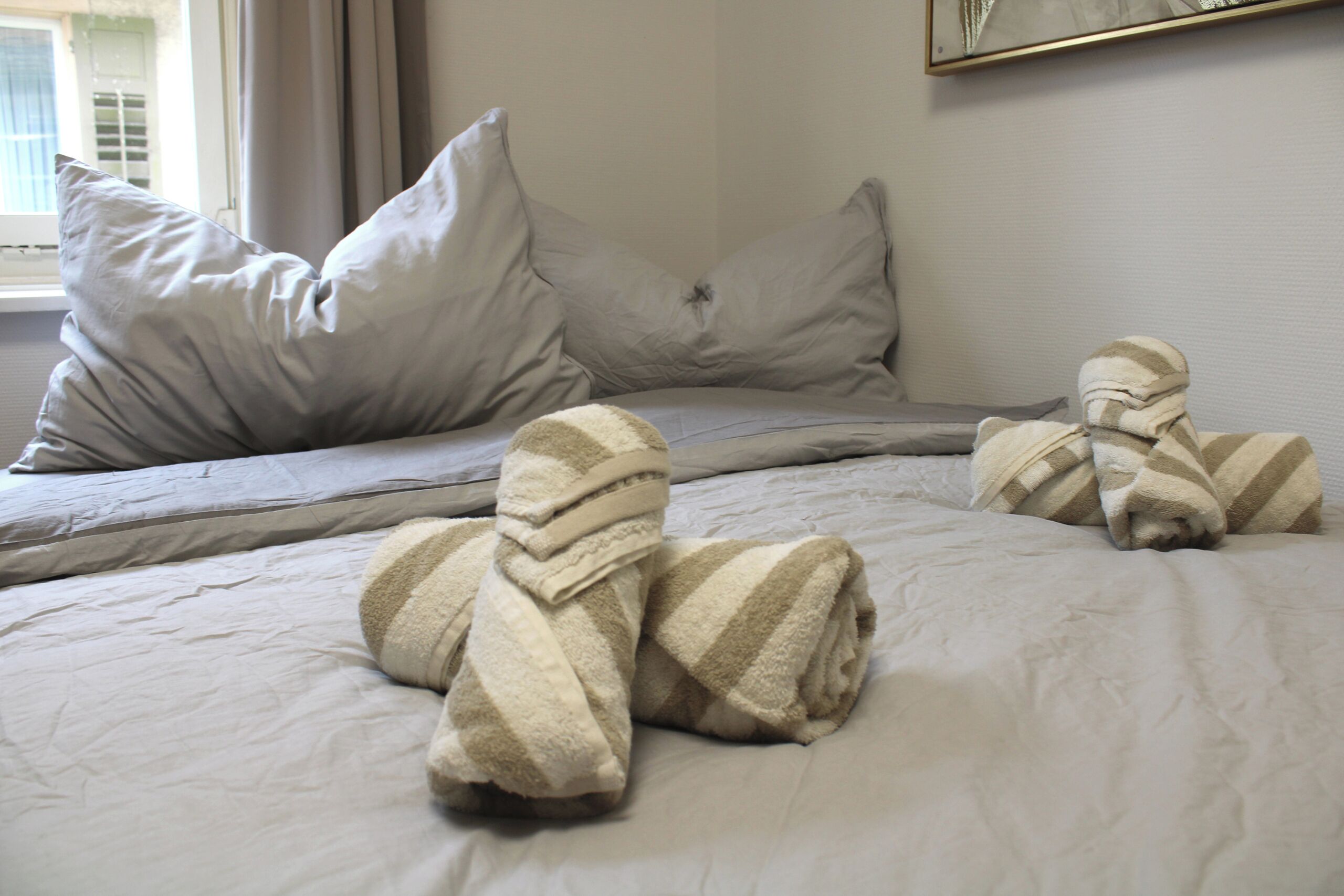 Un letto con cuscini, una coperta e un asciugamano.