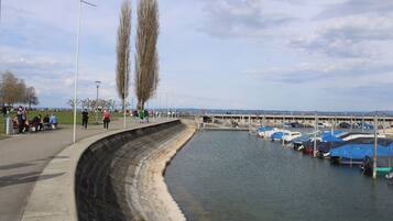 Eine Uferpromenade mit einer gewundenen Böschung, eine Reihe von Booten, die an der rechten Seite festgemacht sind, und Menschen, die den Weg entlanggehen.