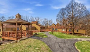 A row of wooden cabins with a covered walkway, a clear sky, and leafless trees. - Farmstead Tee & Ski - Resort Core location, Fireplaces, Dog Friendly (Galena)