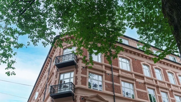 Un edificio de varios pisos con fachada de ladrillo, ventanas grandes y balcones.