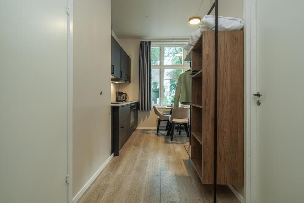 Un pasillo estrecho con una zona de cocina a un lado y un comedor al otro.