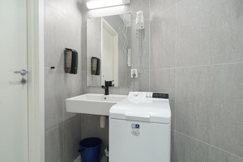 A bathroom with a sink, mirror, and a white washing machine.